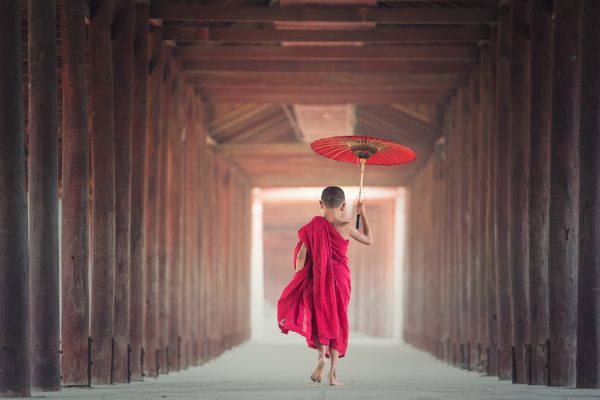 Monk walking through a temple with an Umbrella